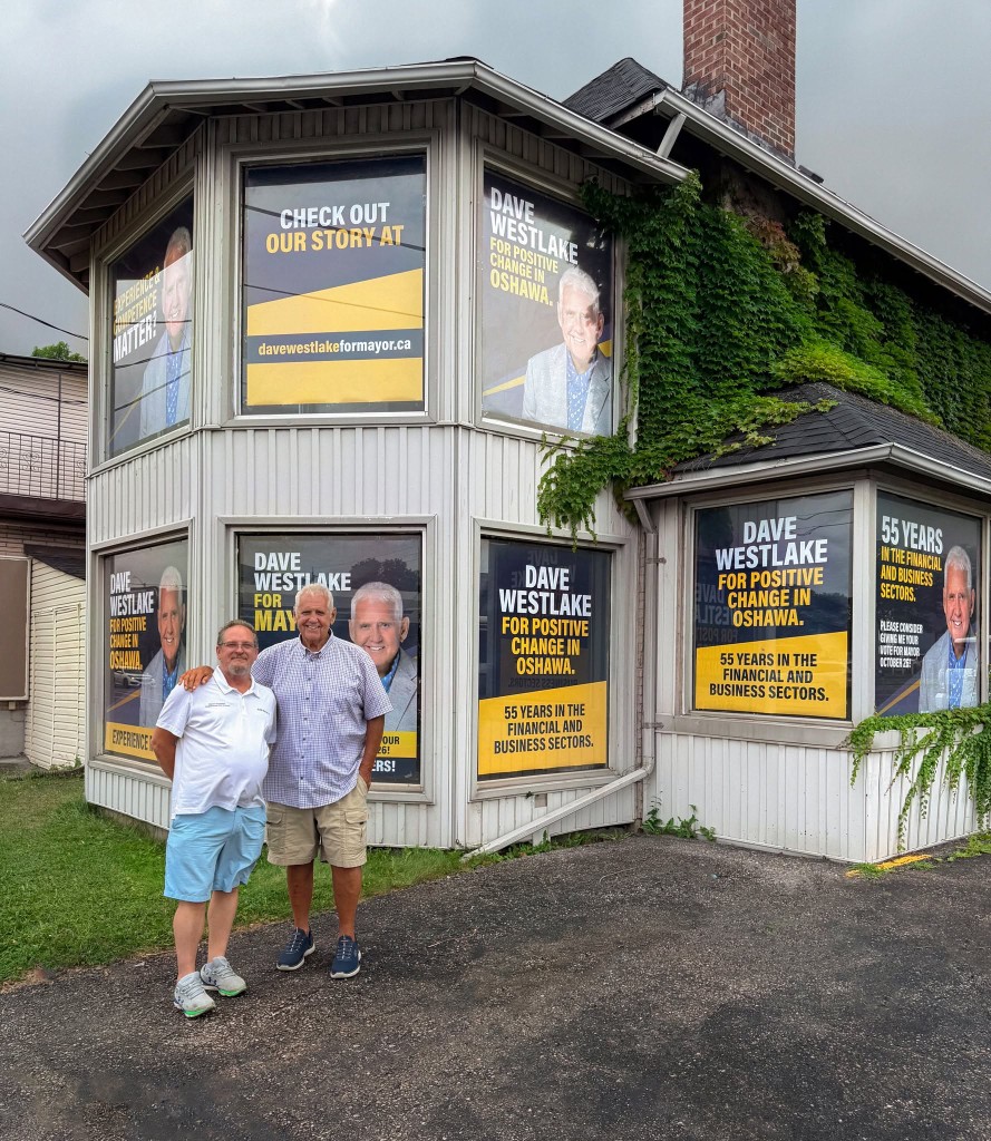 Dave Westlake and Don Rockbrune in front of Dave Westlake for Mayor window posters